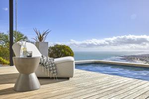 een bank op een terras naast een zwembad bij Kianga in Gordonsbaai