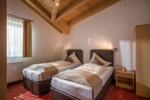 two beds in a room with wooden ceilings at Villa Amsel in Mayrhofen