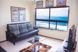 a living room with a couch and a large window at High Tide Beach Condo in Durban