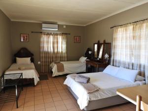 a bedroom with two beds and a table and window at Vastrap Guest Farm in Grünau +85 photos