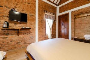 a brick walled bedroom with a bed and a tv at Omah Teras Bata Guesthouse in Yogyakarta