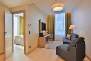a living room with a couch and a chair and a bedroom at Centennial Nexus Hotel Tallinn in Tallinn