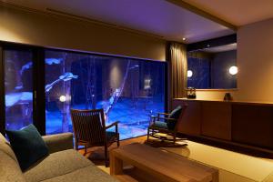 a living room with a large window with a large aquarium at Okujozankei Onsen Kasho Gyoen in Jozankei