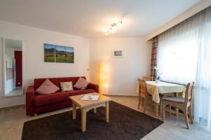 a living room with a red couch and a table at Nebelhorn Appartementhaus in Oberstdorf