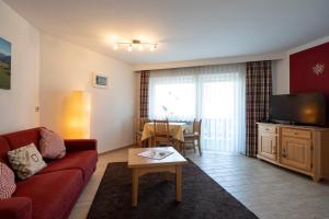 a living room with a couch and a tv and a table at Nebelhorn Appartementhaus in Oberstdorf