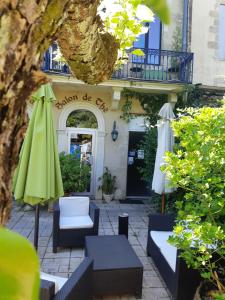 an outdoor patio with umbrellas and chairs in front of a building at Appart'Hôtel Les Tilleuls in Saint-Macaire