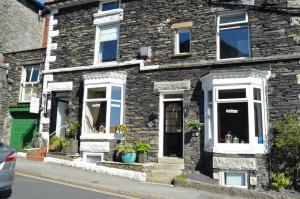 a stone house with white windows and plants on it at All Seasons Rest in Windermere