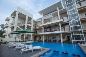 Rovira Suites في دوماغيتي: اطلالة على مبنى مع مسبح وكراسي ومظلة