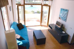 a living room with a blue couch and a television at B16-Dúplex luminoso+ piscina a 150 m del mar in Charco del Palo