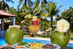 una mesa con una bebida y algo de comida junto a una piscina en Chalés de Peroba, en Maragogi