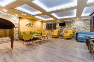 a waiting room with yellow chairs and a piano at Amstel Hattyú Panzió -Érintésmentes bejelentkezés in Győr