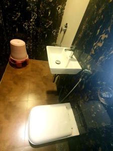 a bathroom with a white sink and a toilet at Hotel Shambuji in Thane