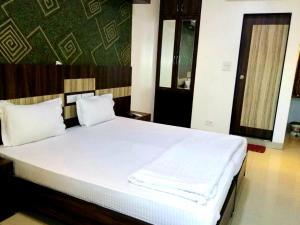 a bed with white sheets and pillows in a room at Hotel Shambuji in Thane