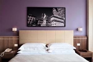 una camera con un letto con una foto sul muro di Hotel Raffaello a Firenze