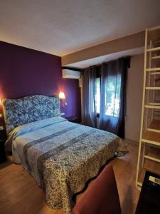 a bedroom with a bed and a purple wall at Hotel Restaurante Las Galias in Zuera