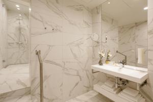 a white bathroom with a sink and a shower at Centennial Nexus Hotel Tallinn in Tallinn