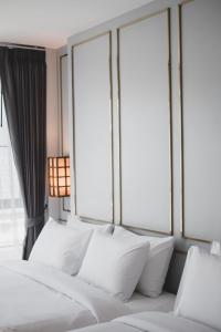 1 cama con almohadas blancas en una habitación con ventanas en The Wing Boutique Hotel en Chiang Mai