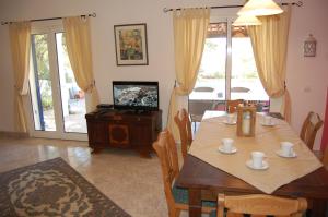 a dining room with a table and a television at Casa dos Amigos-cottage for 6 persons in Estói