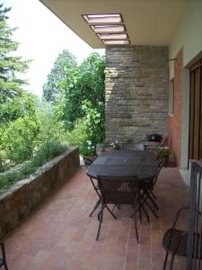 een patio met een tafel en stoelen en een bakstenen muur bij Villa Chiara in Pergine Valdarno