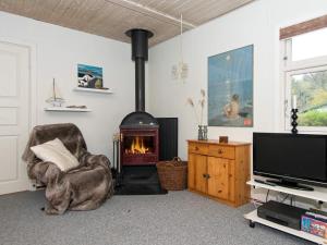 a living room with a fireplace and a chair and a television at 6 person holiday home in Hemmet in Hemmet