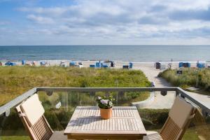 - Balcón con vistas a la playa, mesa y 2 sillas en Ferienwohnanlage Dünenhaus, en Hohwacht