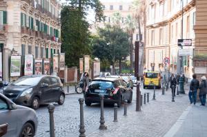 una concurrida calle de la ciudad con coches aparcados en la calle en LHP Suite Napoli Parco Margherita, en Nápoles