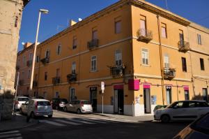 un grand bâtiment jaune avec des voitures garées dans une rue dans l'établissement Bed and Breakfast San Saturnino, à Cagliari