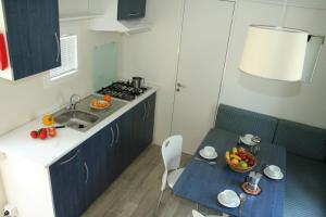 een keuken met een wastafel en een tafel met een fruitschaal bij Happy Camp Mobile Homes in Brioni Sunny Camping in Štinjan