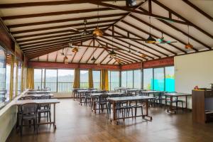 una sala da pranzo con tavoli, sedie e finestre di Green Velvet Resort-Near Pawna Lake a Lonavala