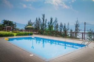 a large swimming pool with a wooden deck at Green Velvet Resort-Near Pawna Lake in Lonavala