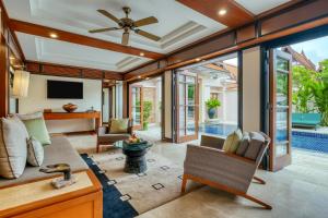 a living room with a ceiling fan and sliding glass doors at Banyan Tree Phuket in Bang Tao Beach
