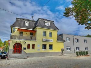 ein gelbes Gebäude mit schwarzem Dach in der Unterkunft Garni-Hotel zur Krone in Schwieberdingen