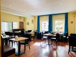 a dining room with tables and chairs and windows at Garni-Hotel zur Krone in Schwieberdingen