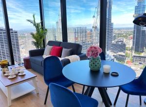 een woonkamer met een bank en een tafel en stoelen bij CBD Fabulous View 2BR high in the sky on Collins in Melbourne