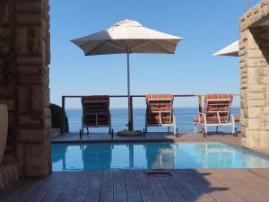 a swimming pool with chairs and an umbrella at Brenton On The Rocks in Brenton-on-Sea
