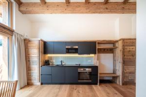 a kitchen with black cabinets and a stove at Wagstätt Residenzen Jochberg by Alpina-Holiday in Jochberg