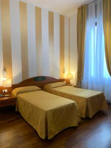 duas camas num quarto de hotel com paredes listradas em Hotel Bogart 2 em Milão