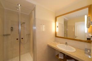 a bathroom with a shower and a sink and a mirror at Hotel & Spa Sonne in Sankt Kanzian