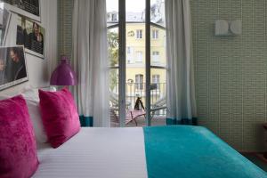 a bedroom with a large bed with pink and blue pillows at Le 123 S&eacute;bastopol - Astotel in Paris