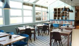 a restaurant with wooden tables and chairs and windows at Wychwood Park Hotel and Golf Club in Crewe
