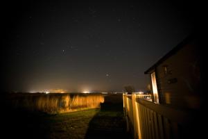 a starry night with a fence and a house at Sea 'n' Stars Platinum Plus Holiday home with Views, Free Wifi and Netflix in Camber