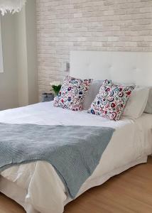 a bedroom with a white bed with pillows on it at Piso MiraCíes- Wifi- Parking- Vistas Ría de Vigo in Vigo