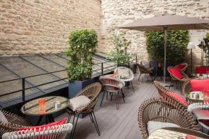 a patio with tables and chairs and an umbrella at Le 123 Sébastopol - Astotel in Paris