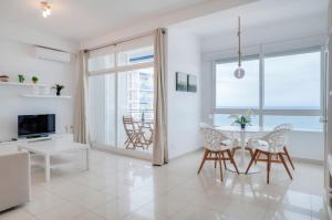 Skol Sea Views Apartments في مربلة: غرفة معيشة بيضاء مع طاولة وكراسي