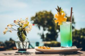 - une boisson et une assiette de nourriture sur une table avec des fleurs dans l'établissement Hotel Chalets Chamarel, à Chamarel