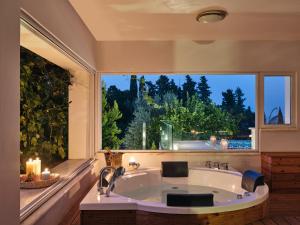 a large bath tub in a bathroom with a large window at Villa Castelletto heated pool jacuzzi in Kipseli