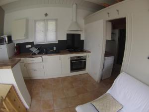 uma pequena cozinha com armários brancos e um sofá branco em le pied marin em Ker Pierre Borny