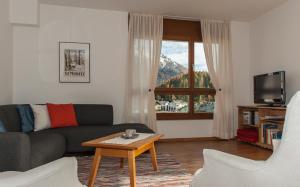 ein Wohnzimmer mit einem Sofa, einem Tisch und einem Fenster in der Unterkunft Chesa Guardamunt in Celerina