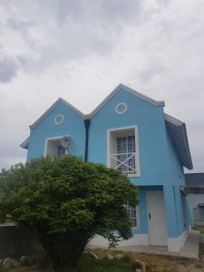 una casa azul con un árbol delante en Complejo La Celeste en Playas Doradas