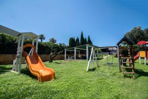 a playground with an orange slide in the grass at Delfino Beach Hotel in Marsala